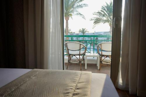 a bedroom with a bed and a balcony with two chairs at Panorama Naama Heights in Sharm El Sheikh