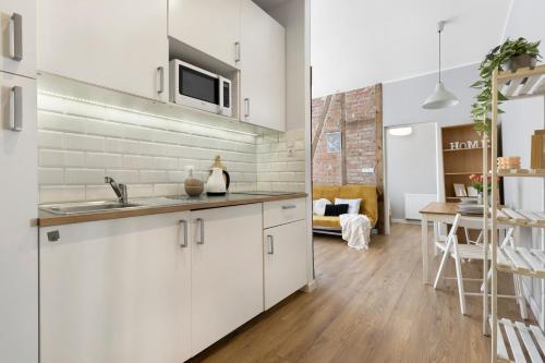 Elite Apartments Stare domki في غدانسك: مطبخ بدولاب بيضاء ومغسلة وطاولة