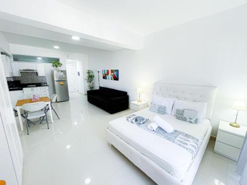 1 dormitorio blanco con 1 cama grande y cocina en ROOFTOP POOL Ducassi Tropicana STUDIO SUITES Deluxe HOTEL Beach Club & SPA, en Punta Cana