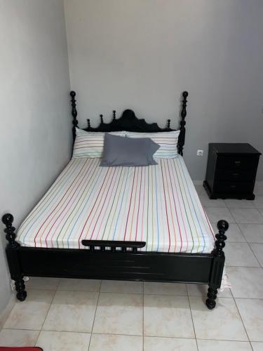 a bed with a black frame in a room at Casa Tchitchi in São Filipe