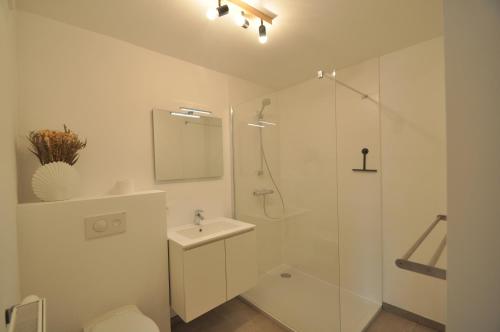 a white bathroom with a shower and a sink at De witte oase 22 in Oostduinkerke