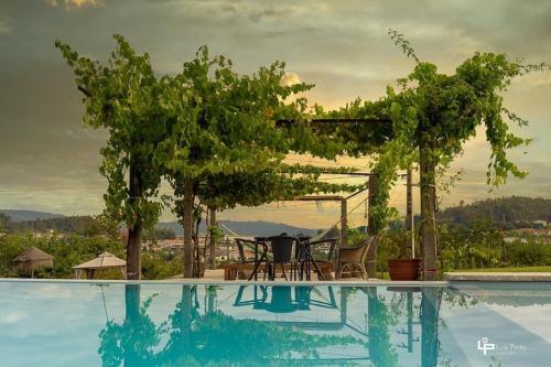 uma piscina com mesa e cadeiras ao lado de uma árvore em Hotel Quinta da Tulha em Guimarães