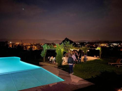 un grupo de personas de pie alrededor de una piscina por la noche en Hotel Quinta da Tulha en Guimarães
