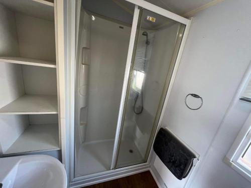 een douche met een glazen deur in de badkamer bij Lyntons 3 bedroom caravan pets stay free in Heacham