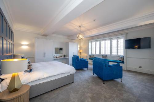 a bedroom with a bed and two blue chairs at The Golden Lion Hotel in Hunstanton