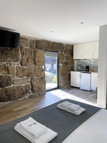 a kitchen with a stone wall and two white towels at Hotel Quinta da Tulha By VimaHotels in Guimarães