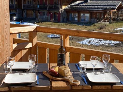 - une table avec une bouteille de vin et une assiette de nourriture dans l'établissement Appartement Neuf 3 Ch. Proche Pistes avec Terrasse, Wifi et Garage - Les Gets - FR-1-623-356, aux Gets