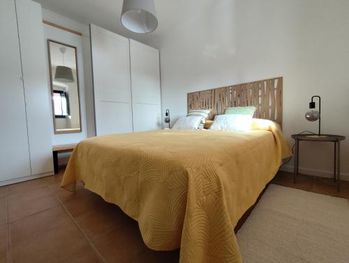 a bedroom with a large bed with a yellow blanket at Vila Nova Guest House in Mértola