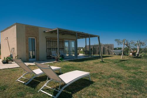two chairs and a table in a yard at NEW Exclusive Lodges, Marzamemi, Noto in Pachino