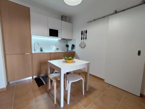 a kitchen with a white table and two stools at Vila Nova Guest House in Mértola