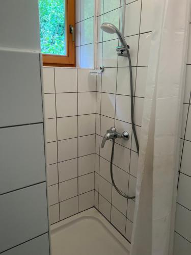 eine Dusche mit einem Schlauch in einem weiß gefliesten Bad in der Unterkunft Hostel Črjanski raj in Črna na Koroškem