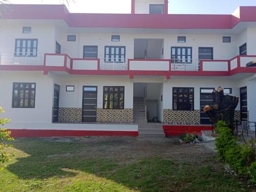a large white building with red accents and a man standing in front of it at Shri govind guest house in Kotdwāra