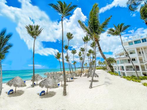 einen Strand mit Palmen und ein Gebäude in der Unterkunft ROOFTOP POOL Ducassi Tropicana STUDIO SUITES Deluxe HOTEL Beach Club & SPA in Punta Cana