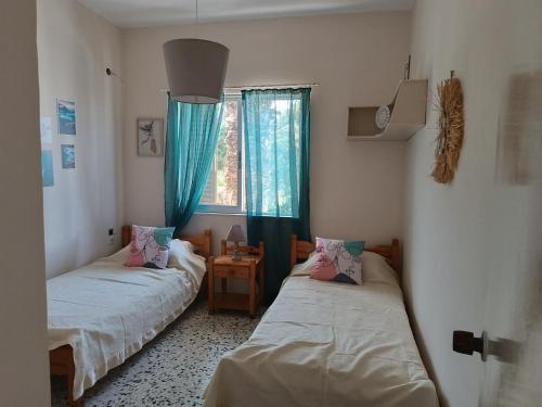two twin beds in a room with a window at ARMIRA HOME in Kalymnos