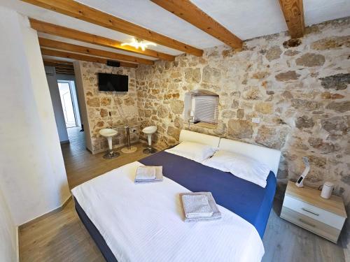 1 dormitorio con 2 camas y pared de piedra en Nanna's little paradise, en Hvar