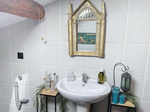 ein Bad mit einem Waschbecken und einem Wandspiegel in der Unterkunft Le sanctuaire des sorciers in Calmont