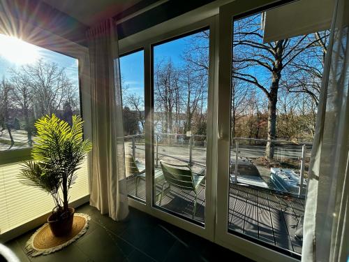 a screened porch with windows looking out at a boat at LITELIVING Cozy Suite - Sauna - Balkon - Parken - BBQ - Modern & Gemütlich in Möhnesee