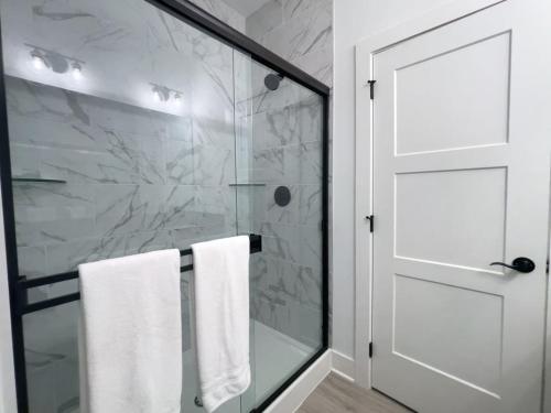 a bathroom with a shower with white towels and a door at Majesty - Work Friendly & Near Downtown in Jeffersonville