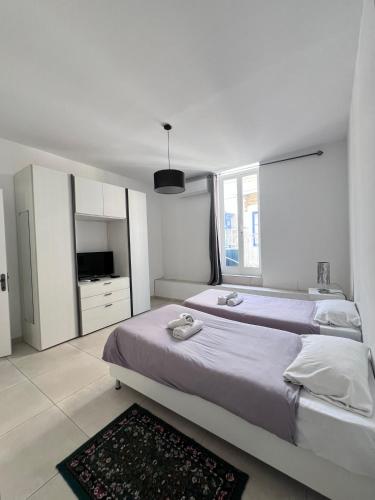 a white bedroom with two beds and a television at Sunshine Court Apartment No 1 in Sliema