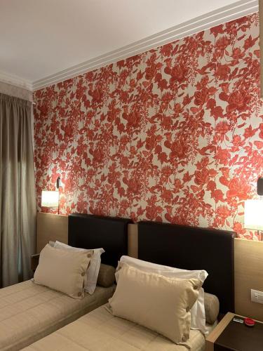 a bedroom with two beds and a red wall at Hotel Montreal in Florence