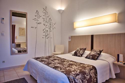een slaapkamer met een groot bed en een spiegel bij La Taverne in Uzès