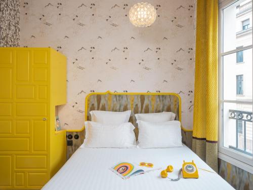 - une chambre avec un grand lit et une tête de lit jaune dans l'établissement Hôtel Crayon Rouge - Louvre Palais Royal, à Paris