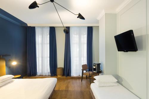 a hotel room with two beds and a flat screen tv at Hôtel Silky by HappyCulture in Lyon