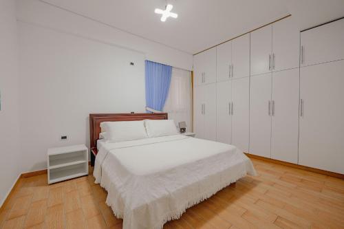 a bedroom with a white bed and white cabinets at Villa Xika in Sarandë
