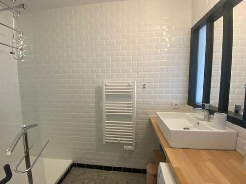 une salle de bain blanche avec un lavabo et un miroir dans l'établissement Brise Marine, à Saint-Gilles-Croix-de-Vie