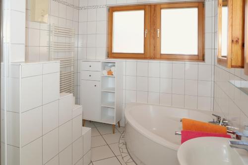Baño blanco con bañera y lavamanos en FeWo Bayha "Im Ort", en Langenargen