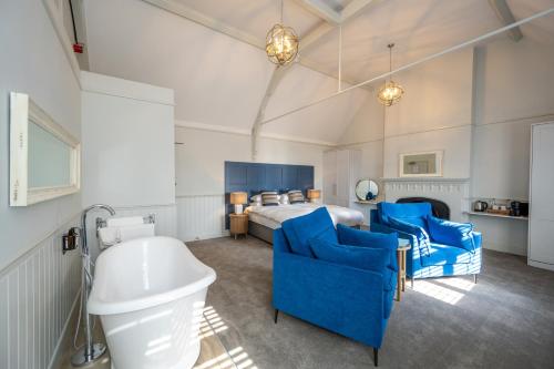 a bedroom with a bed and blue chairs and a tub at The Golden Lion Hotel in Hunstanton