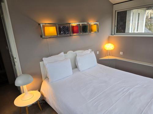 a bedroom with a white bed with a window and a lamp at Le Castel Guesthouse in Bayeux