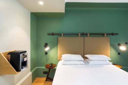 a bedroom with a bed and a tv on the wall at Hôtel Silky by HappyCulture in Lyon