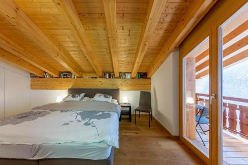 Ce lit se trouve dans un dortoir doté d'un plafond en bois. dans l'établissement Apartment Pipistrelle by Dieckereise, à Verbier
