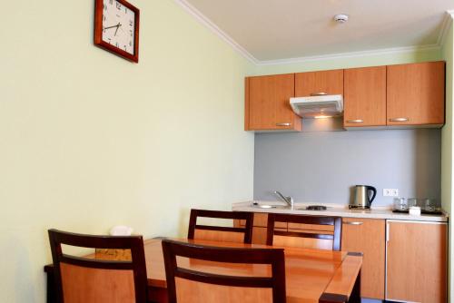 a kitchen with a table and chairs and a clock on the wall at Narantuul Hotel in Ulaanbaatar