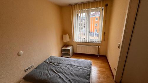 Habitación pequeña con cama y ventana en 2 Zimmer Wohnung am Milaneo en Stuttgart
