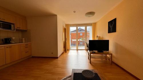 an empty living room with a television and a kitchen at 2 Zimmer Wohnung am Milaneo in Stuttgart