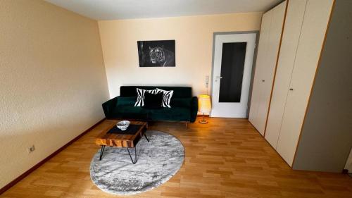 a living room with a green couch and a table at 2 Zimmer Wohnung am Milaneo in Stuttgart