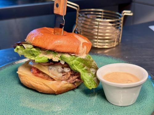 a sandwich on a plate with a cup of dipping sauce at Logis Hôtel & Restaurant Le Vert Bocage in Franqueville-Saint-Pierre