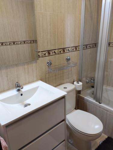a bathroom with a toilet and a sink and a tub at Apartamento Noja Beach in Noja