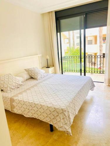 a bedroom with a bed and a large window at Roda Golf. Poolside apartment in Murcia