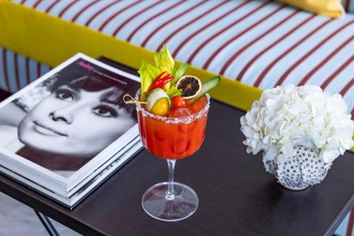 a table with a drink and a picture of a woman at Palazzo Roma - The Leading Hotels of the World in Rome