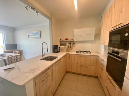 La cuisine est équipée de placards en bois, d'un évier et d'un four micro-ondes. dans l'établissement Appartement face port pour 4 personnes, à Saint-Gilles-Croix-de-Vie