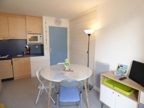 une petite cuisine avec une table et des chaises blanches dans l'établissement Le New Port, à Saint-Gilles-Croix-de-Vie