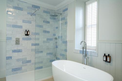 a bathroom with a tub and a glass shower at The Golden Lion Hotel in Hunstanton