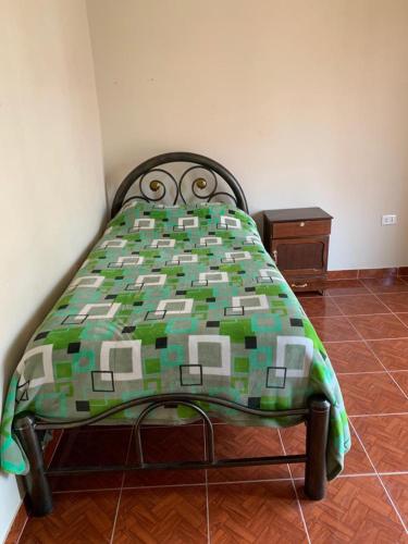 a bedroom with a bed with a green and white comforter at Cabaña Villa San Lorenzo in Tomatas