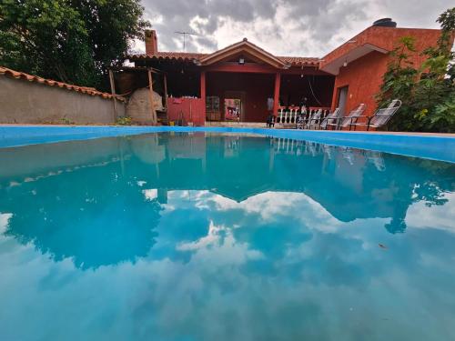 a pool of blue water in front of a house at Cabaña Villa San Lorenzo in Tomatas