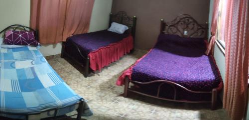 two beds in a room with purple sheets at Cabaña Villa San Lorenzo in Tomatas