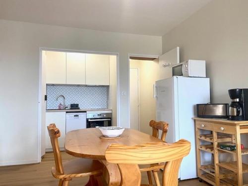 une cuisine avec une table en bois et un réfrigérateur blanc dans l'établissement L'Amiral, à Saint-Gilles-Croix-de-Vie