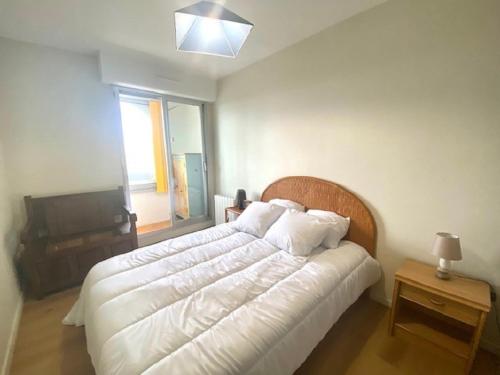 une chambre avec un grand lit blanc et une fenêtre dans l'établissement L'Amiral, à Saint-Gilles-Croix-de-Vie